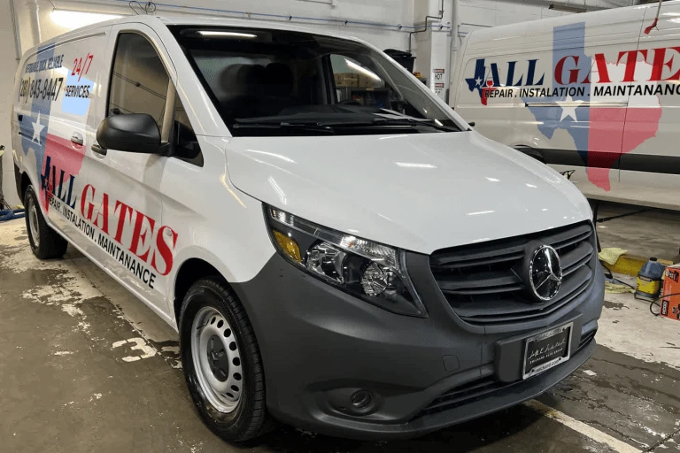 A white utility van is parked in a well-lit, organized garage. The van has "ALL GATES REPAIR, INSTALLATION, MAINTENANCE" written on its side in red and blue letters. Another van with a similar design is in the background. This local Austin business specializes in all your gate needs.