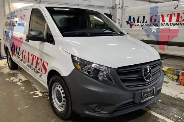 A white van with "All Gates, Repair, Installation, Maintenance" written on the side is parked inside a garage. In the background, a second van with similar branding and text is partially visible. The Austin-based company clearly specializes in gate services.